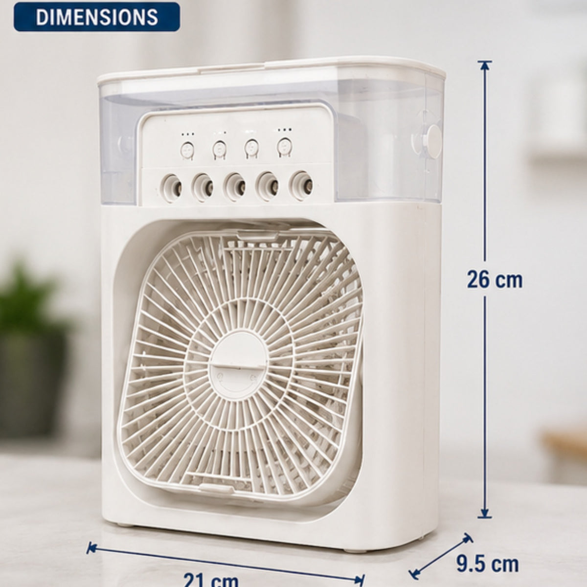 A small white fan with a clear upper cover and measurement annotations showing dimensions of 26 cm height, 21 cm width, and 9.5 cm depth, on a light indoor background.