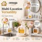 Omega Shop Multi-Location Versatility hand soap dispenser set shown in a bright, modern bathroom and kitchen setting, with circular callouts indicating use for hand soap, dish wash, body wash, and shower area. The dispensers are white with clear front windows showing golden-yellow liquid inside.